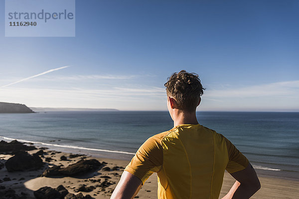 Frankreich  Halbinsel Crozon  sportlicher junger Mann an der Küste mit Blick auf die Küste