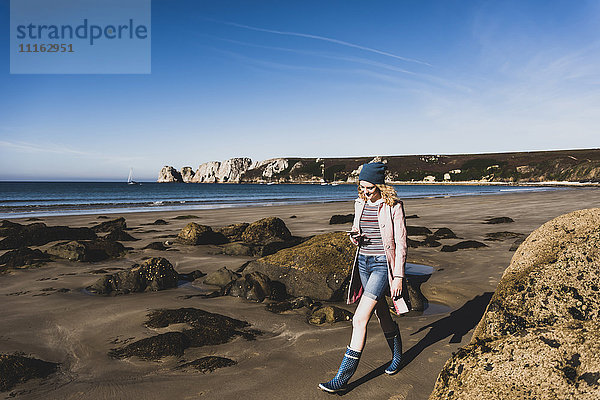 Frankreich  Halbinsel Crozon  Teenagermädchen mit Handy am Strand unterwegs