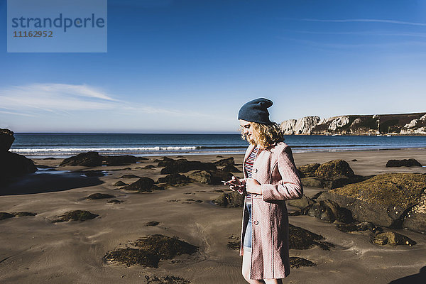 Frankreich  Halbinsel Crozon  Teenagermädchen mit Handy am Strand