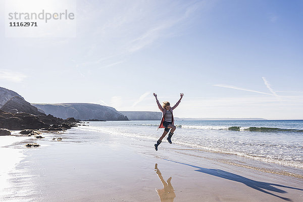 Frankreich  Halbinsel Crozon  Teenager-Mädchen springt vor Freude am Strand