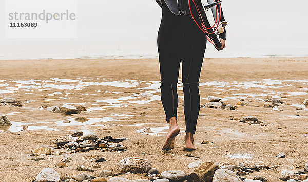 Frankreich  Bretagne  Halbinsel Crozon  Frau mit Surfbrett am Strand unterwegs