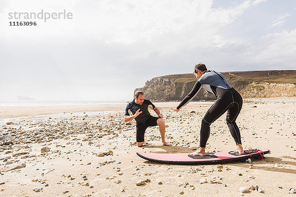 Frankreich  Bretagne  Halbinsel Crozon  Mann unterrichtet Frau beim Surfen am Strand