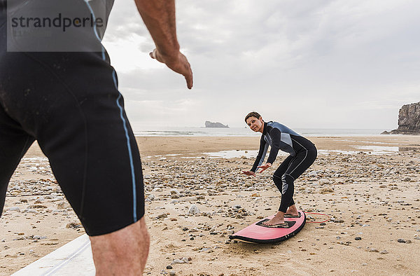 Frankreich  Bretagne  Halbinsel Crozon  Mann unterrichtet Frau beim Surfen am Strand
