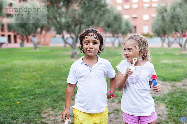 Kleines Mädchen und Junge mit Blasenringen im Park
