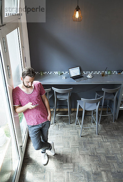 Junger Mann in einem Café mit Handy