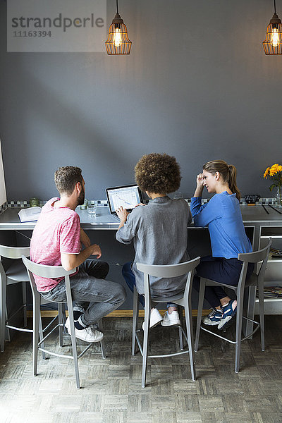 Drei junge Leute in einem Cafe mit Laptop