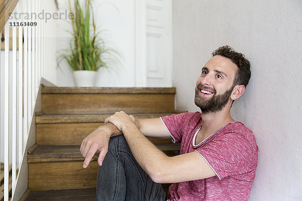 Lächelnder junger Mann auf der Treppe sitzend
