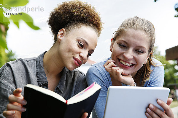 Zwei lächelnde junge Frauen mit Tagebuch und Tablettenausläufern