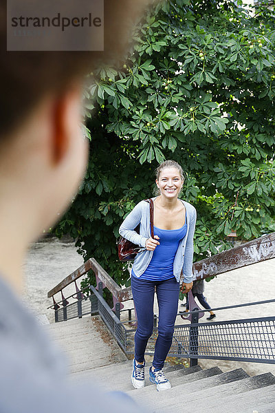 Lächelnde junge Frau beim Treppensteigen im Park