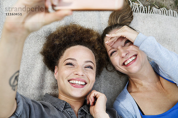 Zwei glückliche junge Frauen  die einen Selfie auf die Decke nehmen.