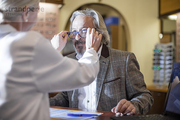 Optiker hilft Kunden bei der Auswahl neuer Brillen