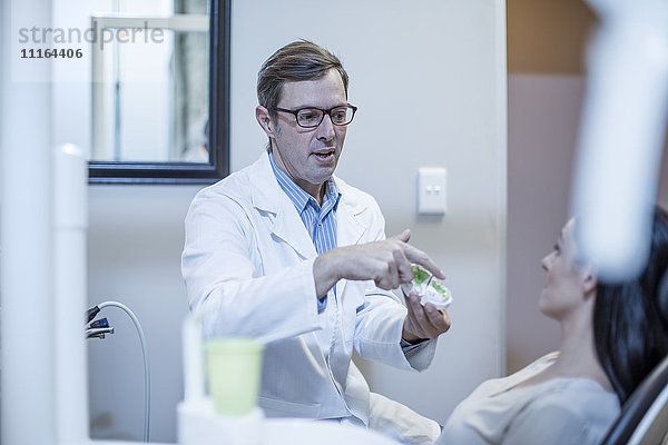 Zahnarzt mit Zahnform im Gespräch mit dem Patienten