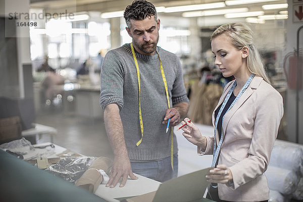 Modedesigner und Schneider arbeiten in der Werkstatt zusammen