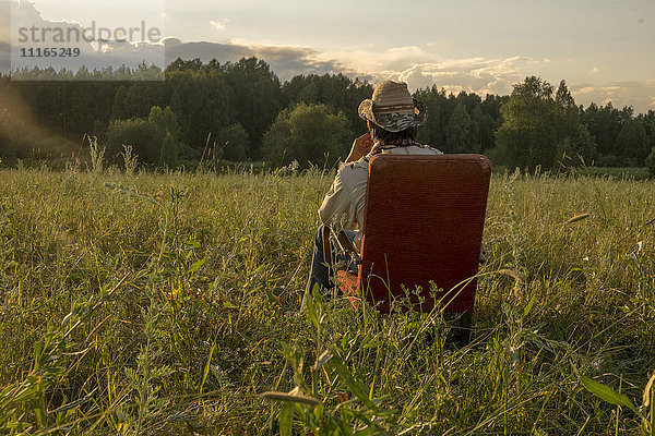 Mari Mann sitzt auf einem Stuhl in einem Feld