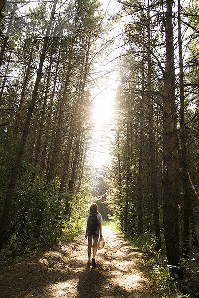 Kaukasische Frau geht auf einem von Bäumen gesäumten Waldweg
