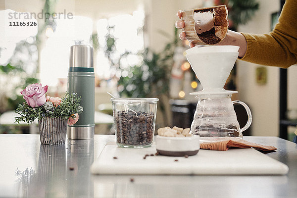 Eine Person  die in einer Küche Filterkaffee zubereitet.