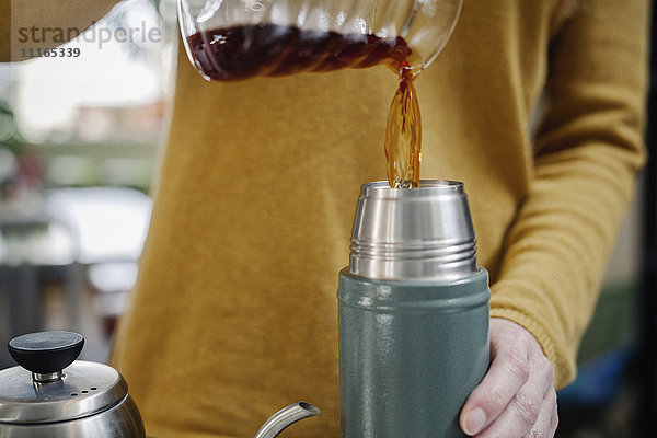 Eine Frau gießt Kaffee in eine Flasche.