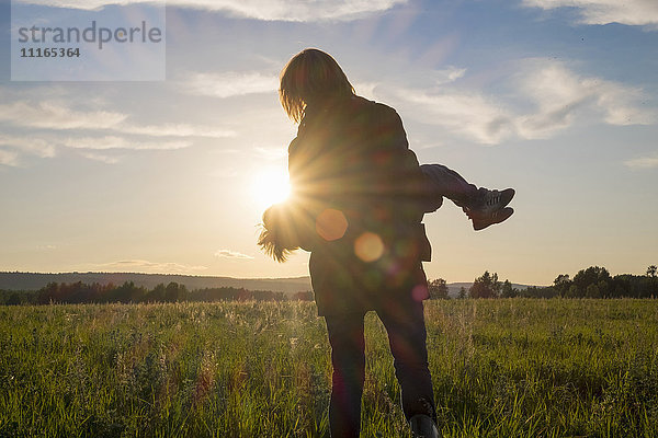 Frau mit Sohn auf einem Feld bei Sonnenuntergang