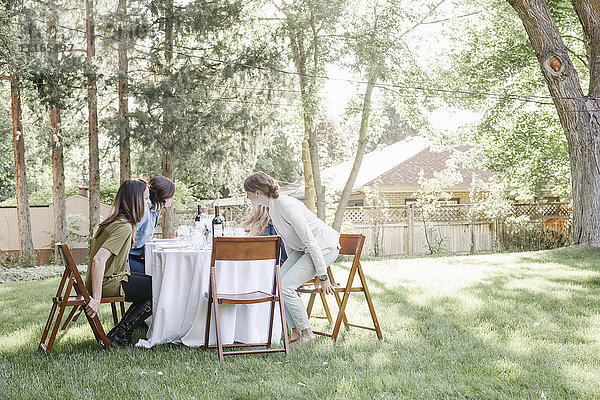 Gruppe von Frauen  die in einem Garten um einen Tisch sitzen.