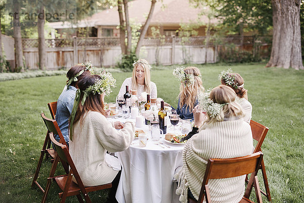 Eine Gruppe von Freundinnen versammelte sich um einen Tisch  in einem Garten  aß und trank.