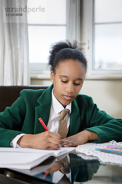 Schwarzes Mädchen in Schuluniform bei den Hausaufgaben