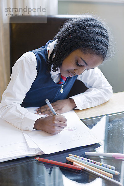 Schwarzes Mädchen in Schuluniform bei den Hausaufgaben