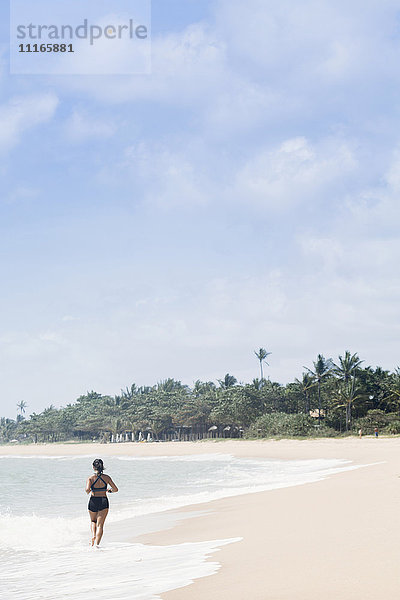 Mixed Race Mädchen läuft am Strand in den Wellen