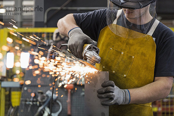 Kaukasischer Arbeiter schleift Metall in einer Fabrik