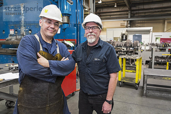 Lächelnde Arbeiter posieren in der Fabrik