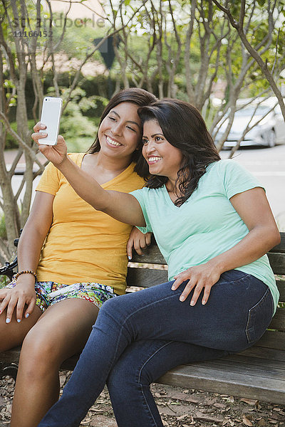 Hispanische Mutter und Tochter posieren für ein Selfie mit dem Handy