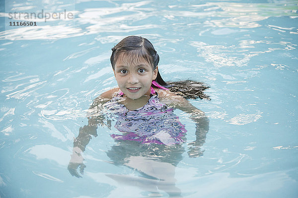 Lächelndes hispanisches Mädchen im Schwimmbad