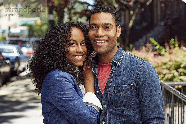 Lächelndes Paar posiert auf dem Bürgersteig der Stadt