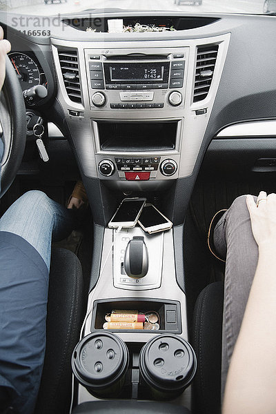 Autoreise. Zwei Frauen sitzen in einem Auto  Kaffeetassen auf der Konsole zwischen den Sitzen.