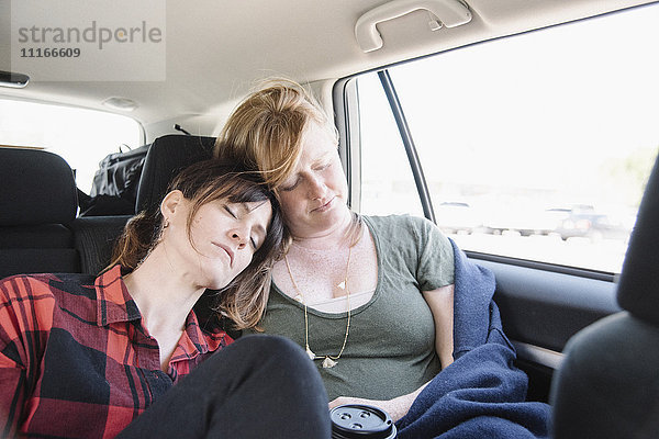 Zwei Frauen in einem Auto auf einer Autoreise  beide schlafend auf dem Rücksitz  fahren zusammen.