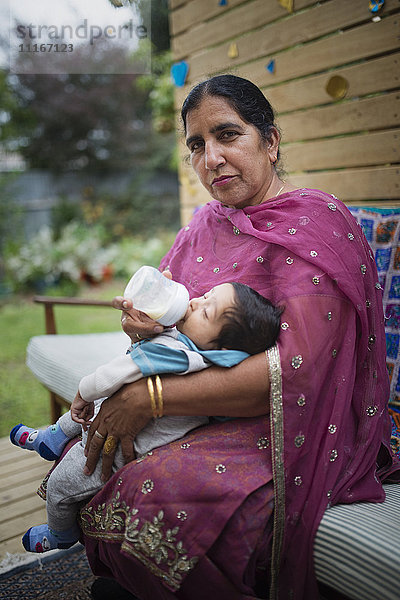 Indische Großmutter füttert ihren Enkel mit der Flasche