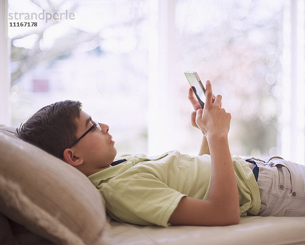 Mixed Race Junge texting auf Handy in der Nähe von Fenster