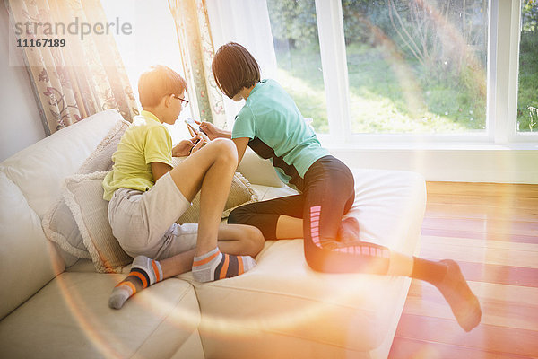 Mixed Race Bruder und Schwester texting auf Handy in der Nähe von Fenster