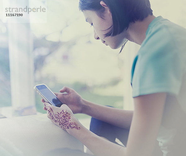 Mixed Race Mädchen texting auf Handy in der Nähe von Fenster