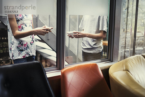 Mixed Race Bruder und Schwester texting auf Handys hinter Fenster