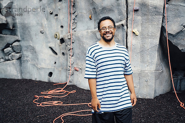 Mixed Race Mann lächelnd in der Nähe der Kletterwand