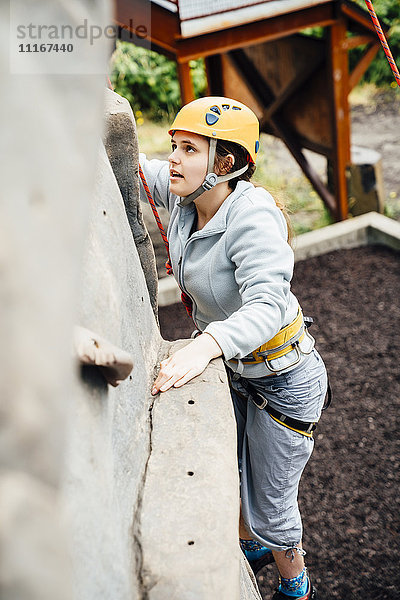 Kaukasische Frau beim Klettern an der Kletterwand