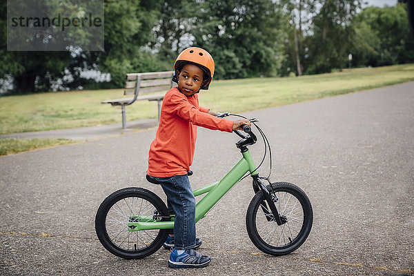 Schwarzer Junge mit Helm auf dem Fahrrad sitzend