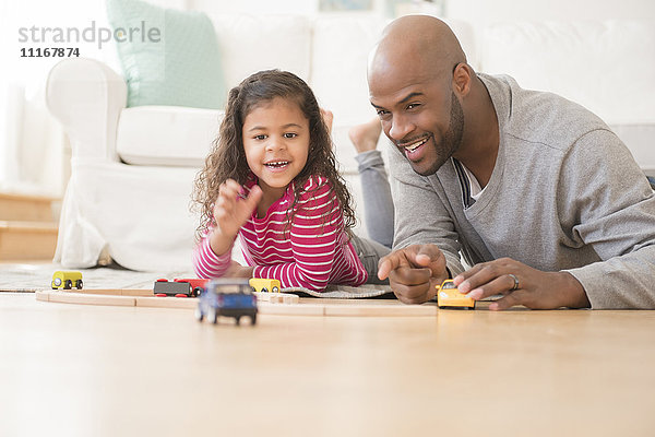 Vater und Tochter spielen mit Spielzeugautos auf dem Boden