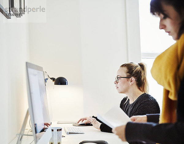 Zwei Frauen in einem Büro  eine mit einem Computer.