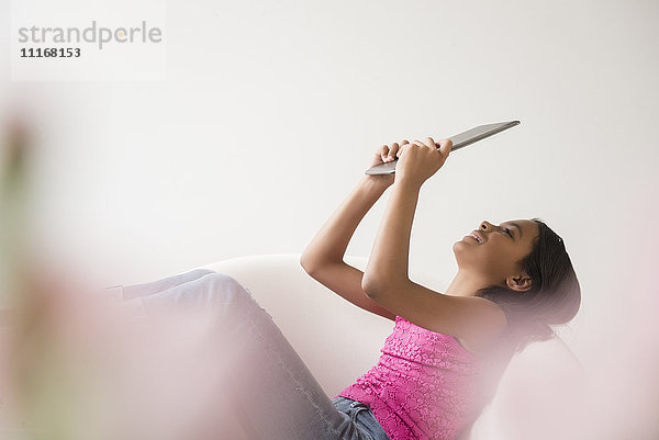 Mixed-Race-Mädchen entspannt sich im Sessel mit digitalem Tablet