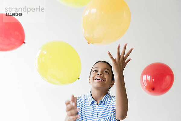 Mixed Race Mädchen wirft Luftballons