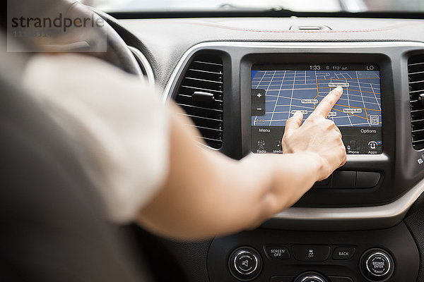 Gemischtrassige Frau  die eine Touchscreen-Navigationskarte im Auto benutzt