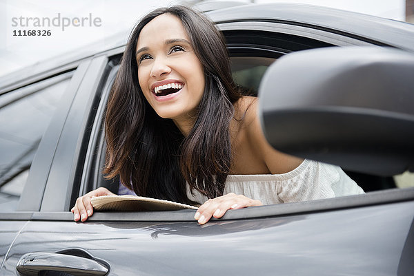 Lächelnde Mixed Race Frau lehnt sich aus dem Autofenster
