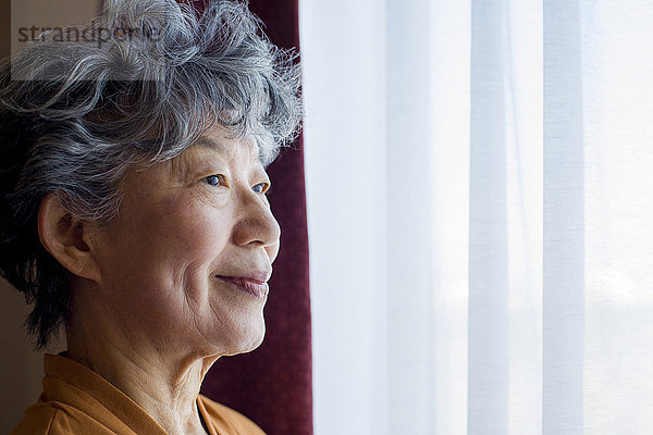 Lächelnde Japanerin am Fenster stehend