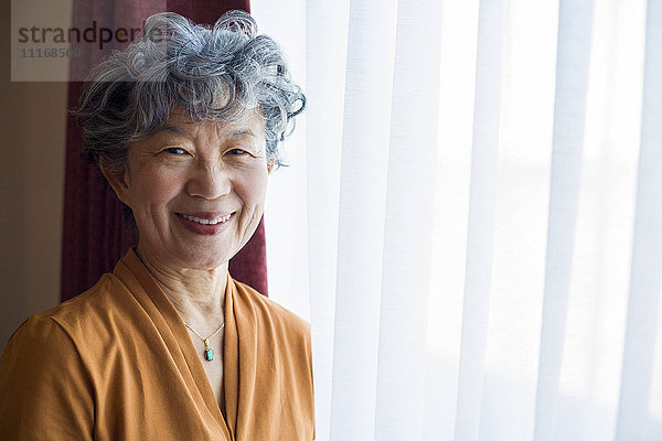 Lächelnde Japanerin am Fenster stehend